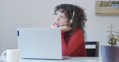 A young female sitting at her office desk with a headset and workingの写真素材