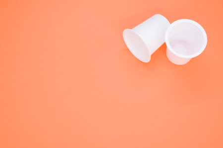 A closeup shot of disposable plastic cups isolated on an orange backgroundの写真素材