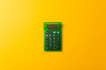 A top view of a green calculator isolated on a yellow backgroundの写真素材