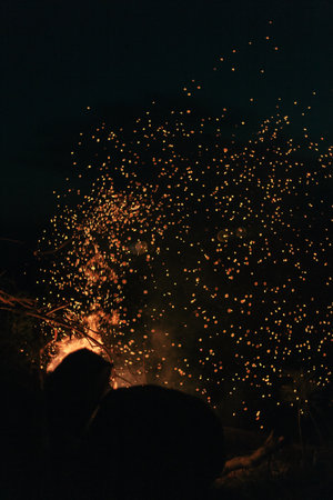 Burning hot sparks flying from the fire in the background of the night sky