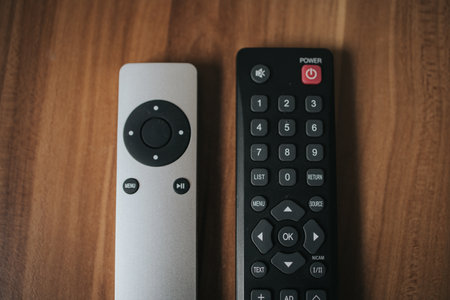 A top view shot of two different remote controls of  TV on a wooden background.の写真素材