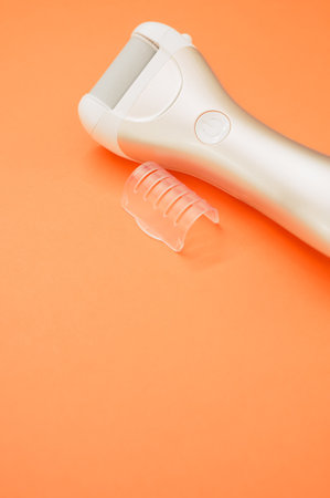 A vertical shot of an electric foot file isolated on an orange backgroundの写真素材