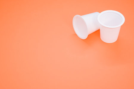 A closeup shot of disposable plastic cups isolated on an orange backgroundの写真素材