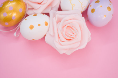 A top view of cute decorative eggs for Easter and roses isolated on a pink background
