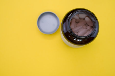 A top view of a bottle of medical pills isolated on a yellow backgroundの写真素材