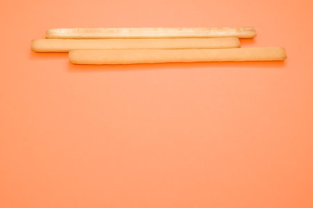 A closeup of three breadsticks on an orange surfaceの写真素材
