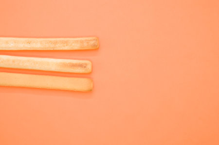 A top view of three breadsticks on an orange surfaceの写真素材
