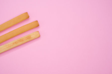 A top view of three breadsticks on a pink surfaceの写真素材