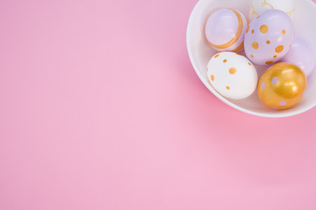 A bowl of decorative Easter egg decorations on a pink surfaceの写真素材
