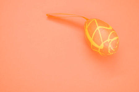 An orange decorative Easter egg decoration on an orange surface