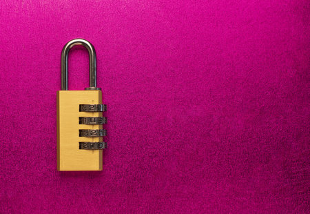 A closeup shot of a combination padlock with a safety code on a pink background - copy space