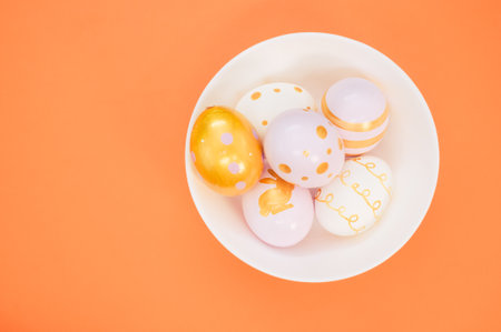 A bowl of decorative Easter egg decorations on an orange surfaceの写真素材
