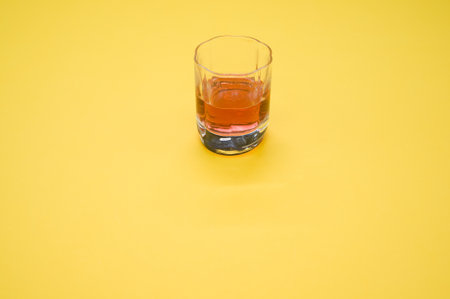 A glass with red liquid on a yellow surface