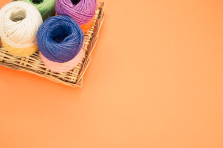 A high angle shot of colorful yarns on an orange surface under the lights