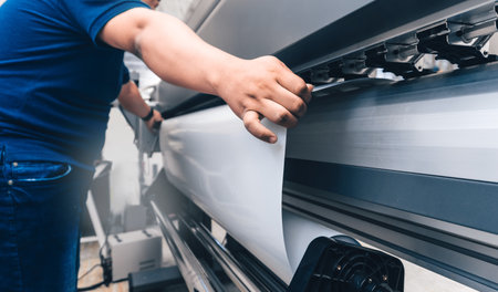 A closeup shot of the hands of a male working on the printing machine