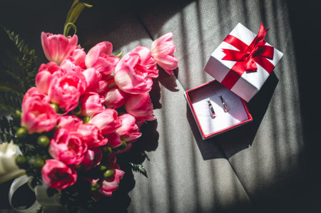 A top view of wedding rings and the bride's bouquet under the sunlight