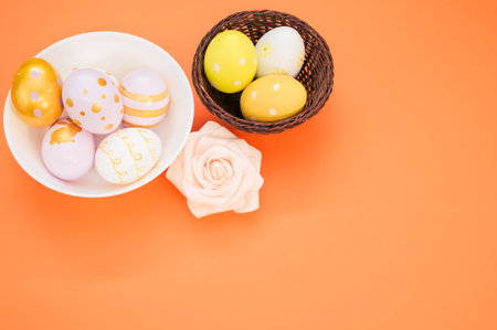 The bowls with Easter egg decorations on an orange surface