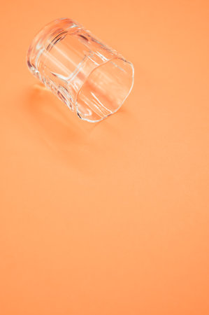 A vertical shot of a shot glass under the lights isolated on an orange backgroundの写真素材