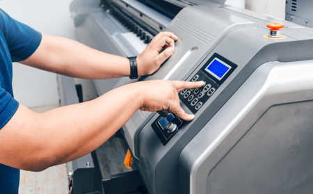 A closeup shot of the hands of a male working on the printing machineの写真素材