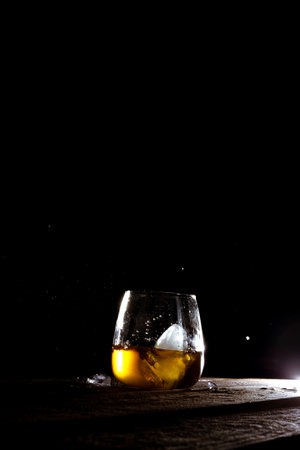 A vertical shot of a refreshing drink with an ice cube over black backgroundの写真素材