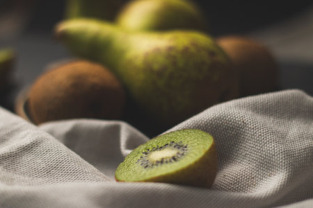 A closeup of delicious ripe kiwis and pears on a tray on the tableの写真素材