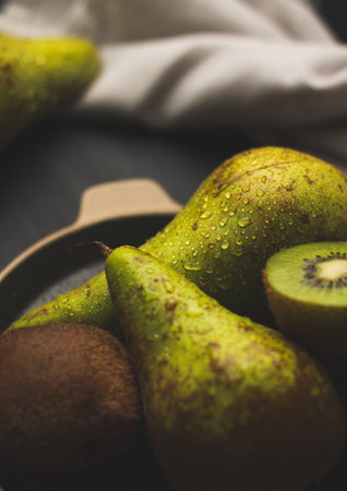 A vertical shot of ripe kiwis and pears on a tray on the table with a tablecloth on itの写真素材
