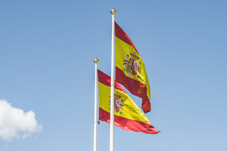 A beautiful shot of the flag of Spain winding against the clear blue skyの写真素材