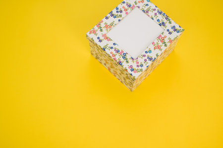 A cardboard box with a floral pattern on a yellow background with space for textの写真素材