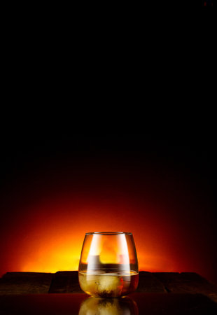 A vertical shot of a glass of whiskey isolated on a dark backgroundの写真素材