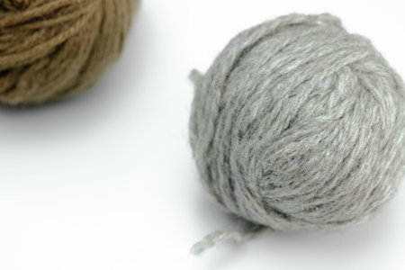 A closeup shot of gray and brown knitting yarn balls on a white surface