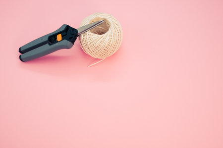 A top view of scissors on the knitting yarn isolated in the pink background with a copy space