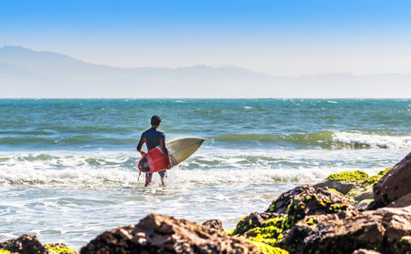 A surfer with a surfing board in wavy sea