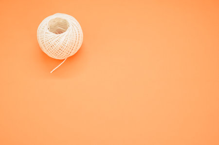 A white ball of twine isolated on an orange background