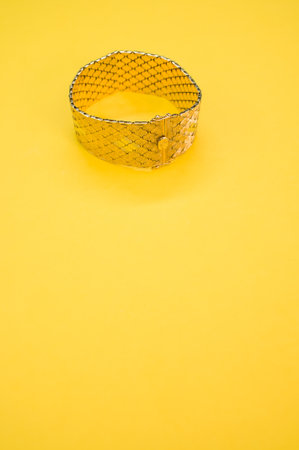 A vertical shot of a vintage golden bracelet isolated on a yellow backgroundの写真素材
