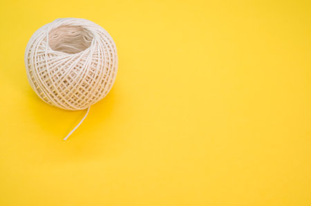 A white ball of twine isolated on a yellow backgroundの写真素材