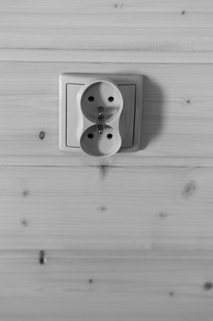 Electric white plastic sockets on a wooden walの写真素材