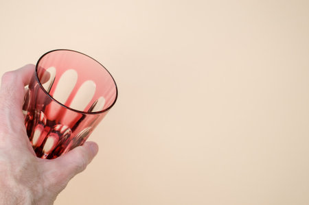 A closeup shot of a male hand holding an empty glass isolated on a pink backgroundの写真素材