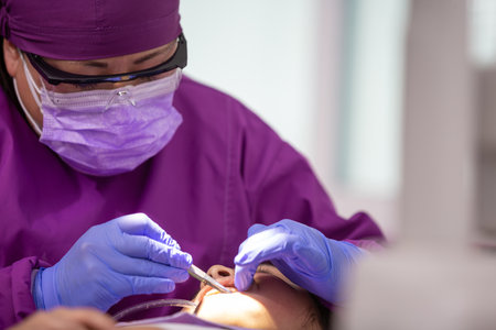 A closeup of a Mexican female dentist doing dental treatment on the young girlの写真素材