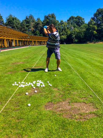 Golfer Training Golf Swing on Driving Range in a Sunny Day in Switzerland.の写真素材