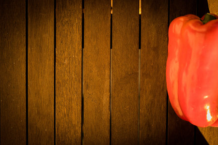 A closeup shot of a red bell pepper on a wooden surfaceの写真素材