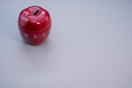 An apple-shaped kitchen timer isolated on light blue backgroundの写真素材