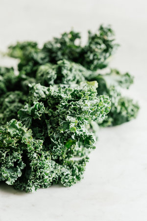 A closeup shot of fresh green curly kale leaves on a white background