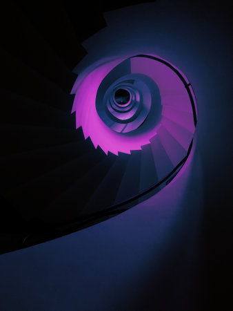A vertical low angle shot of a tall spiraling staircase in aesthetic purple colorの写真素材