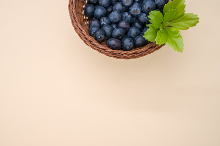 A closeup shot of blueberries in a basket on a beige backgroundの写真素材