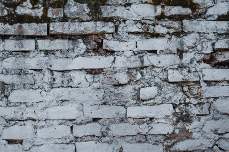 A closeup shot of a brick wall with worn-out and old white paintの写真素材