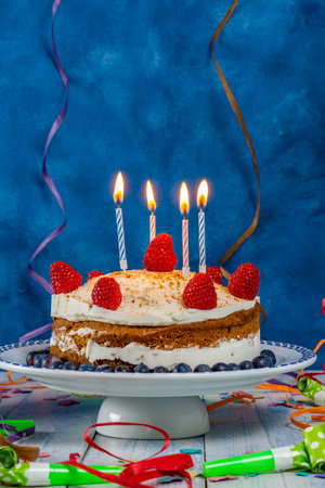 birthday cake with cream and raspberry sponge cake with candles and streamersの写真素材