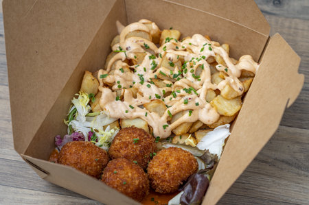 A closeup shot of a box with fries, sauce, and meatballs