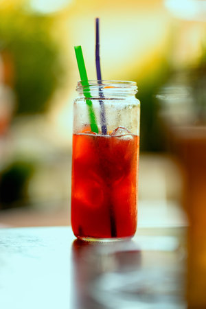 A vertical shot of a red cocktail on a tall clear glass on a wooden surfaceの写真素材