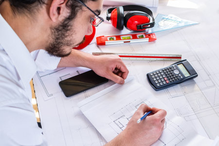 A side view of an Israeli architect-engineer working on a blueprintの写真素材