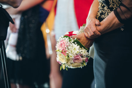 A bridal bouquet in the hands of a senior woman attending a wedding ceremonyの写真素材